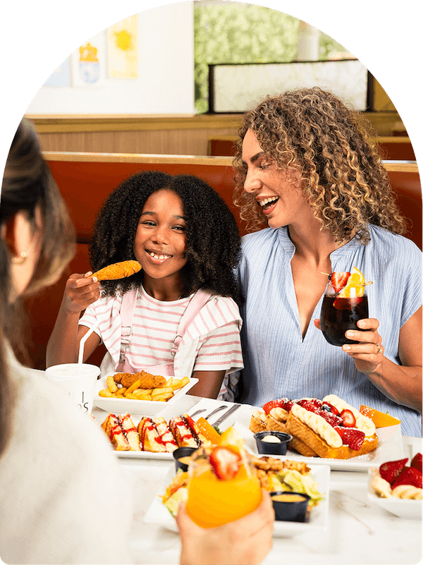 Mother and daughter enjoying a kids meal at Keke's Breakfast Cafe with chicken tenders, fries, French toast, and fresh fruit