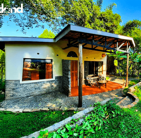 Modern safari cottage with covered veranda and seating area surrounded by lush tropical gardens at a Uganda lodge