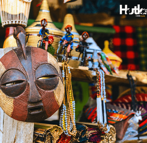 Colourful African handcrafted souvenirs including wooden masks, beaded necklaces and woven baskets at a Uganda craft market