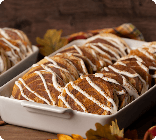 Tray of golden pastries drizzled with icing, arranged for catering