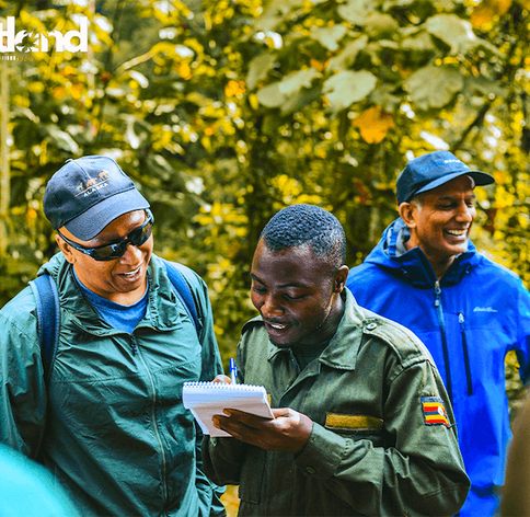Guide speaking to tour group member during gorilla trekking tour in forest