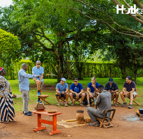 Hutland Tours travellers gathered around a local cultural demonstration during a community visit on a Uganda safari
