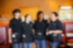 Four Keke's Breakfast Cafe team members in branded uniforms standing together in the dining area