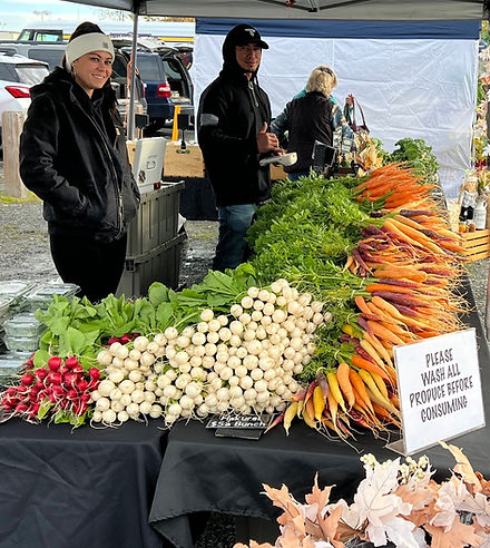 Two people standing at a table covered in fresh produce for sale