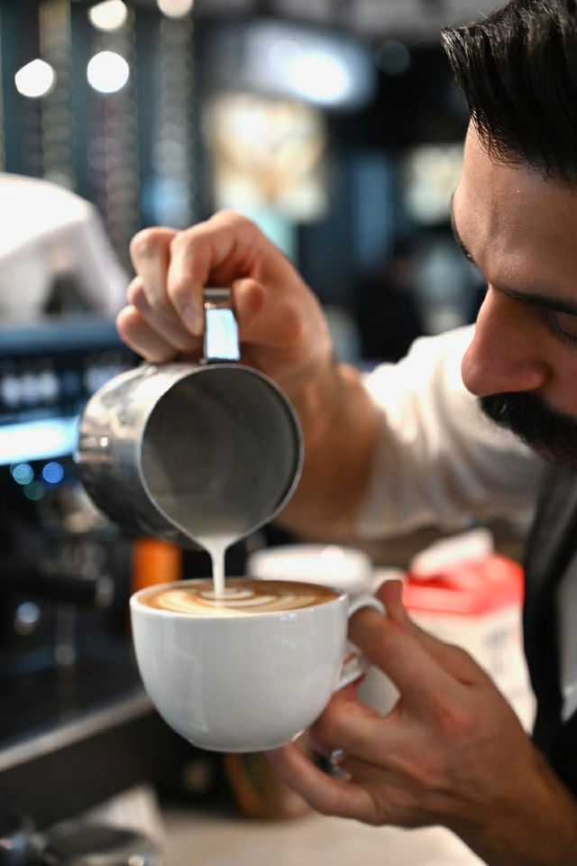 Barista pouring milk to create latte art.