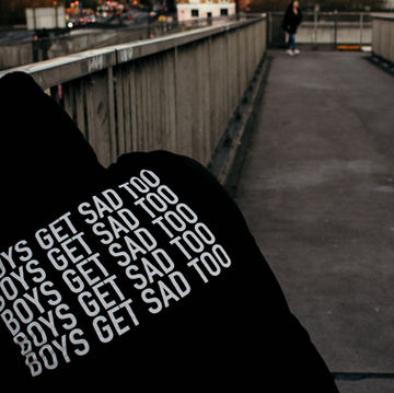 Man in Hooded jumper with "Boys Get Sad Too" written on it 