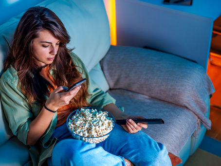 A woman uses a remote control and a smart phone