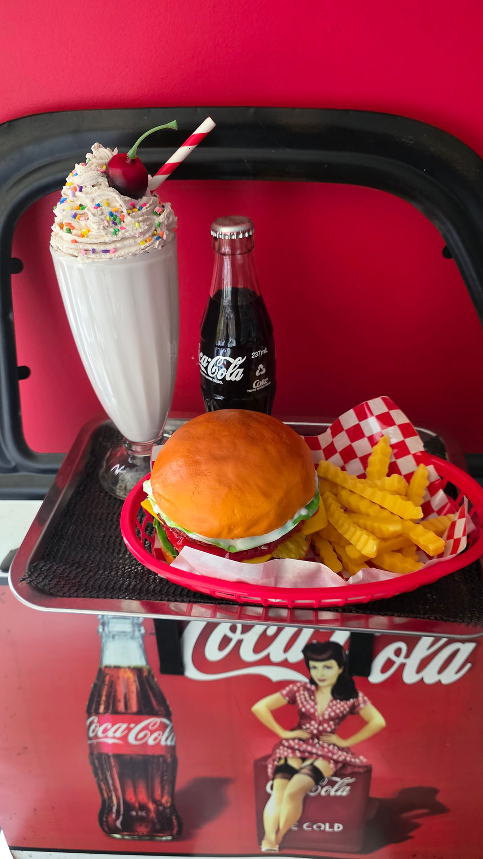 Eye-level view of a tall glass filled with a creamy vanilla milkshake topped with whipped cream and a cherry