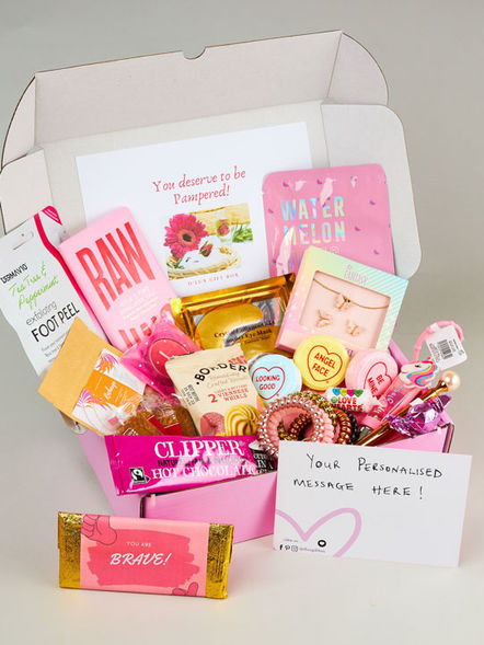 Pink girly gift box with a high number of items arranged in a nice composition, with custom wrapped chocolate bar and handwritten card in front.