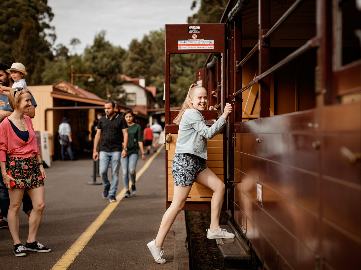 Girl stepping onto open sided carriage at Belgrave Station.
