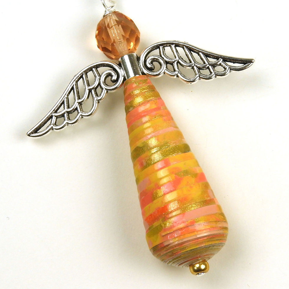 Orange, coral, and gold paper bead angel ornament laying diagonally on a white background.