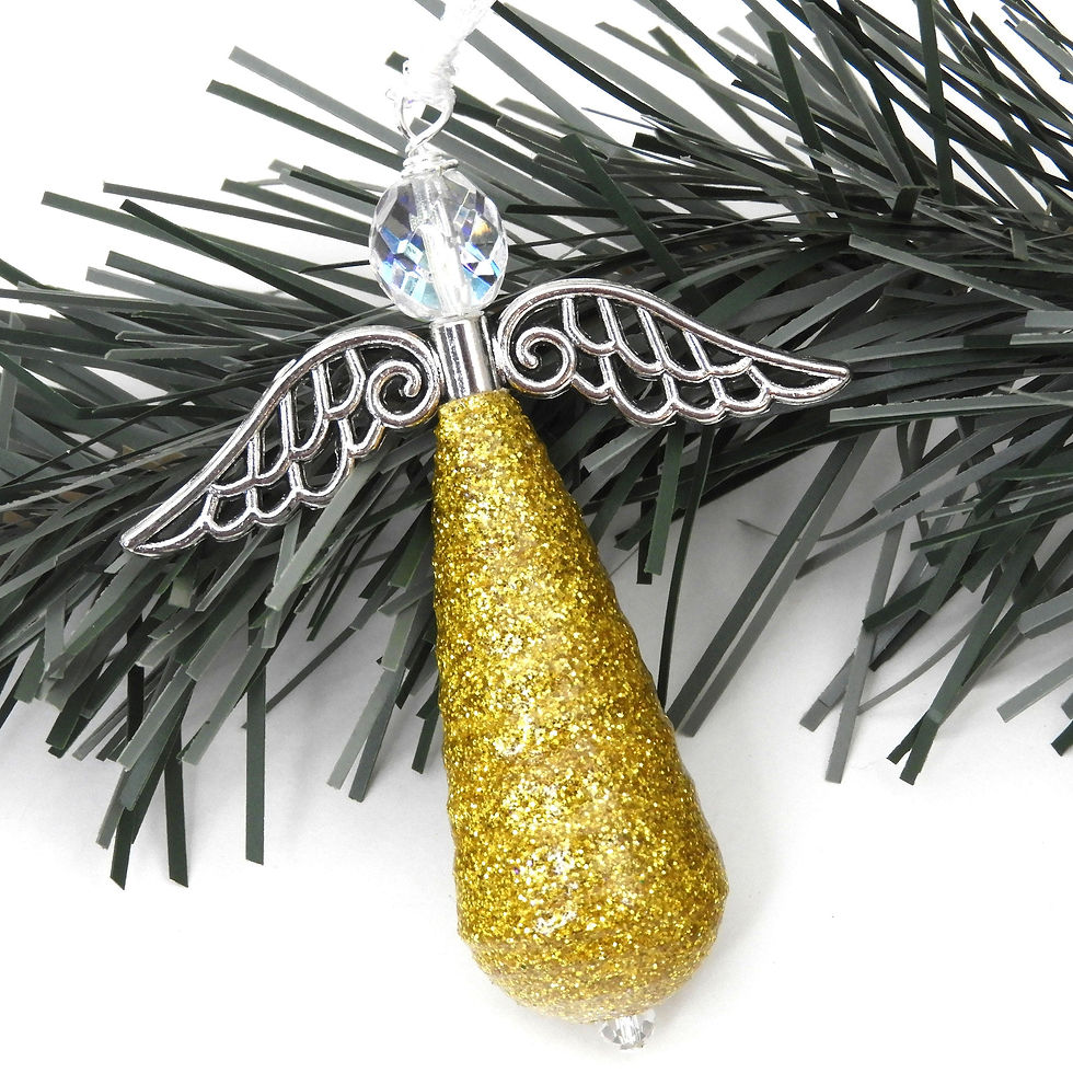 Thumbnail: Yellow gold glitter paper bead angel standing in front of driftwood.