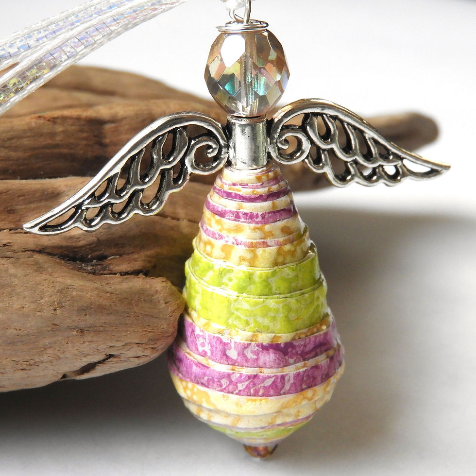 Thumbnail: Purple and green paper bead angel ornament standing in front of driftwood.