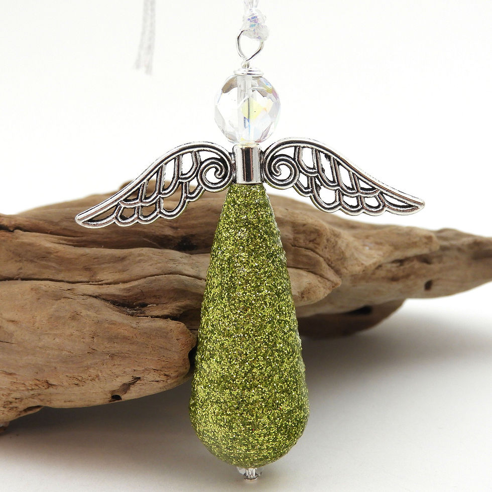 Green glitter paper bead angel ornament standing in front of driftwood.