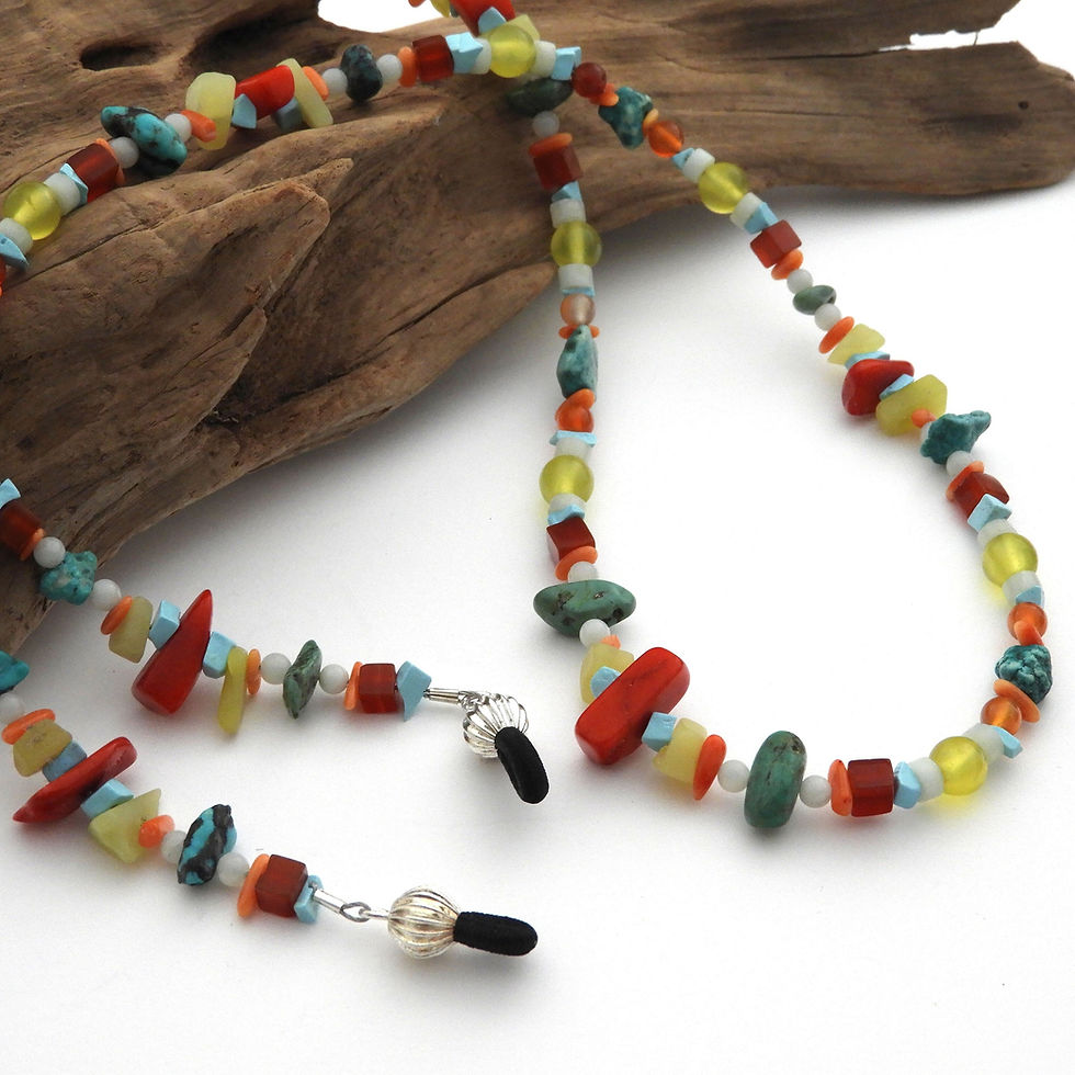 Thumbnail: Natural stone and coral beaded eyeglass chain draped over a piece of driftwood.