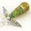 Thumbnail: Orange, green, blue, and gold abstractly painted paper bead angel ornament laying diagonally on a white background.