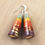 Thumbnail: Teal, mustard, red, and purple paper bead earrings on a wood background.