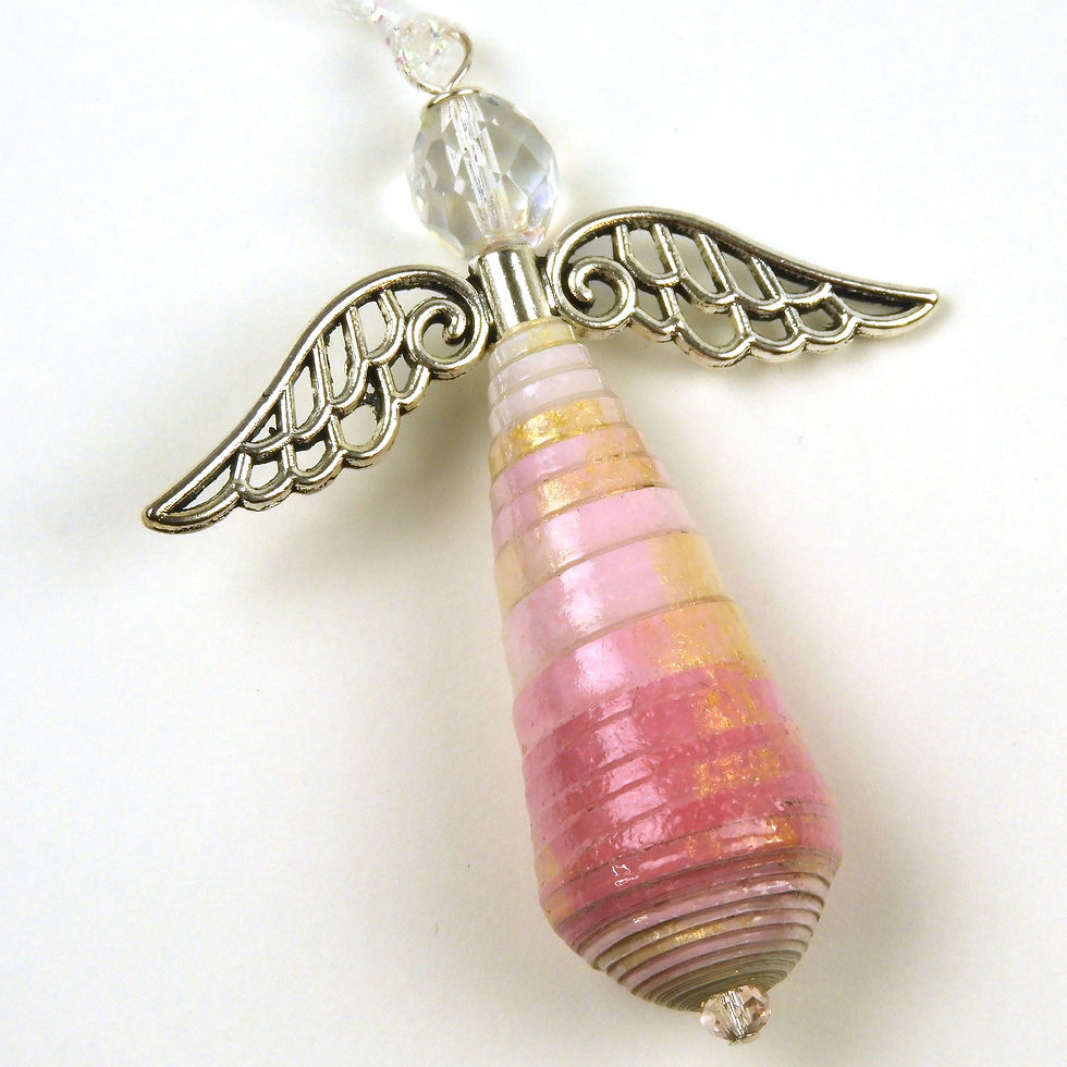 Shades of pink ombre paper bead angel ornament laying diagonally on a white background.