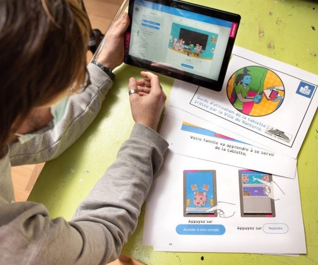 Personne tenant le guide de prise en main des tablettes numériques prêtées par la ville de Nanterre