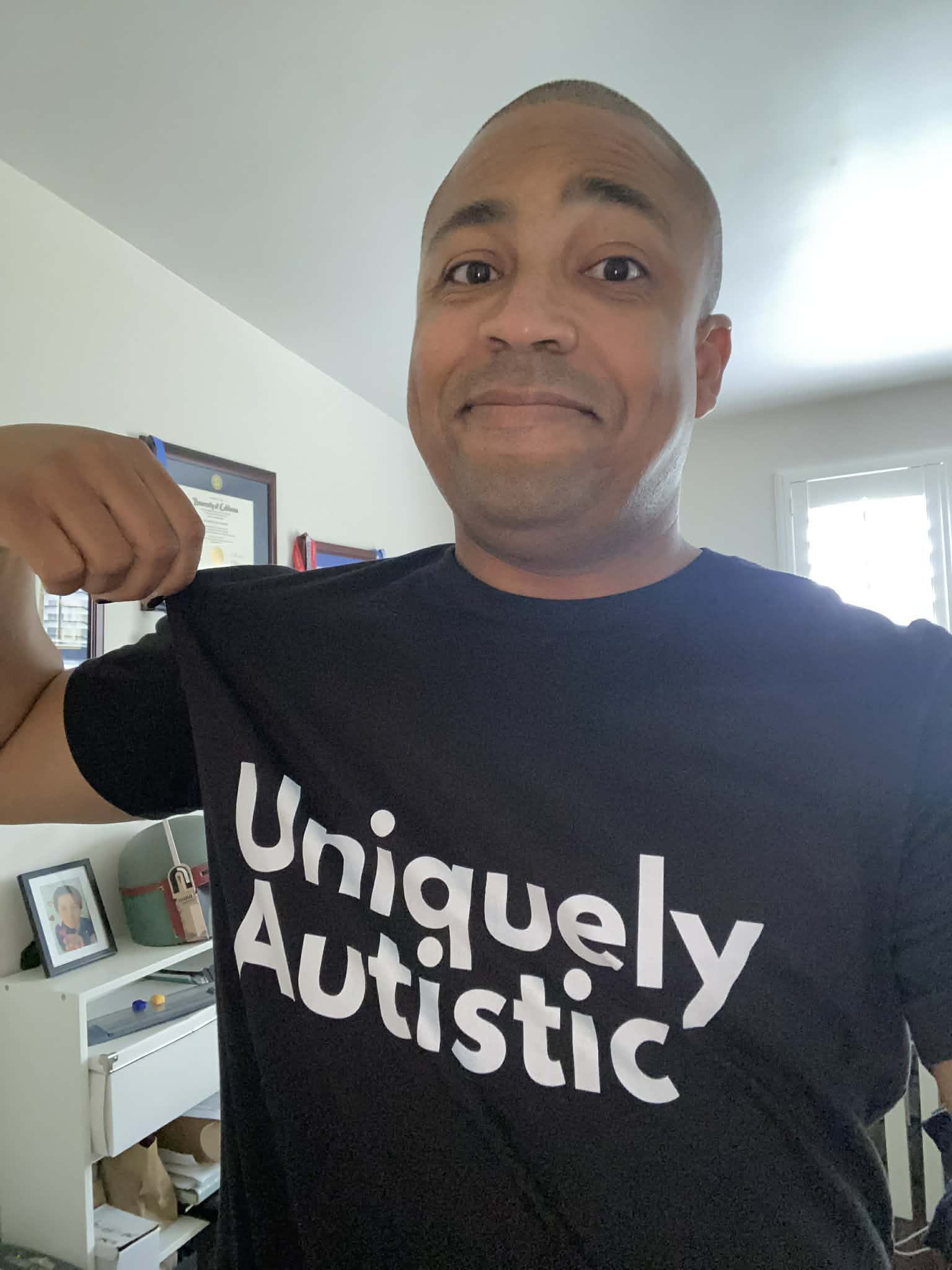 Rolondo Talbott smiling and wearing a shirt that reads Uniquely Autistic