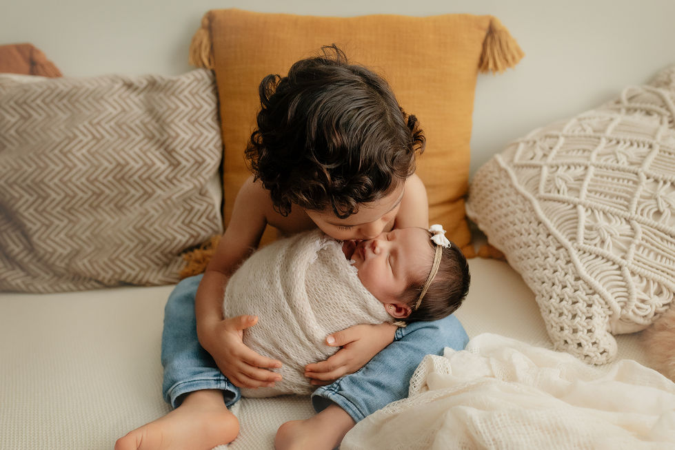 Toddler big brother kissing newborn baby sister in Westchester studio session.