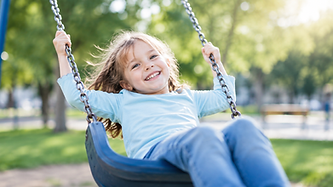 Fröhliches Kind beim Schaukeln im Park, Versicherung und Vorsorge für Kinder und Familien in Oberösterreich