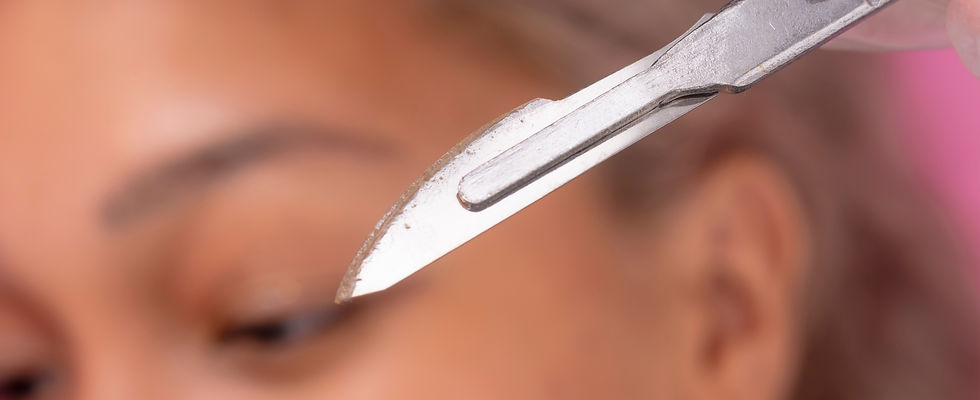 Closeup shot of the scalpel used for dermaplaning procedure, with the client behind.jpg