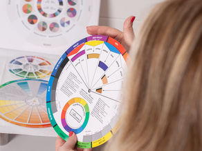 photograph of partial back of head, looking over shoulder at a colour wheel. In the background are colour theory tools.