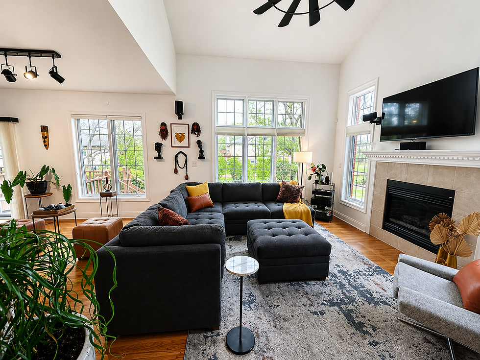 Staged living room with dark sectional sofa, fireplace, and large windows