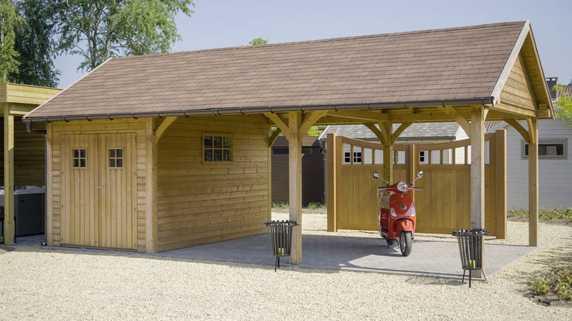 Landelijk tuinhuis met zadeldak en een overkapping om een voertuig onder te zetten.
