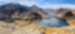 Mountain landscape with rugged peaks, clear blue skies, and two tranquil lakes. Brown and green terrain contrasts with the vivid water.