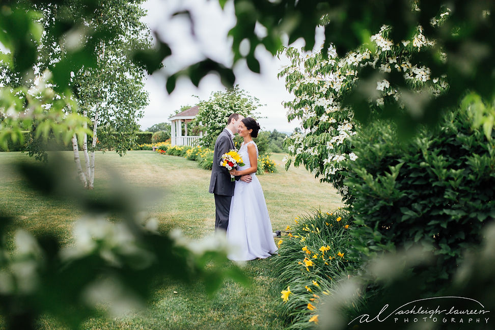The couple stands in the grass, surrounded by the scenic beauty of Dell-Lea Wedding Venue.