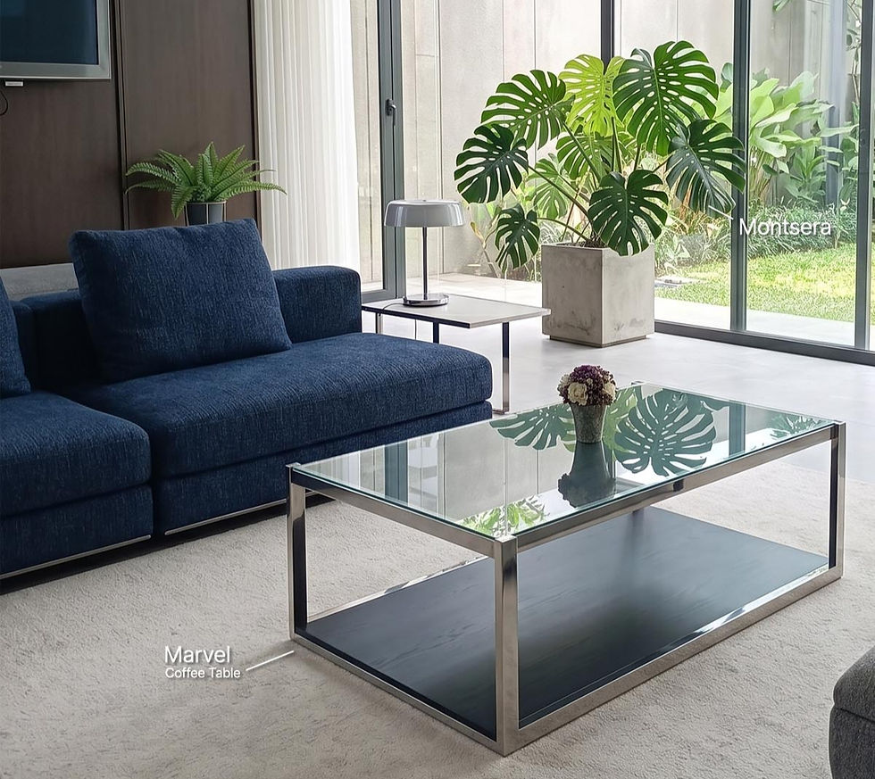 Ruang tamu modern: sofa biru, meja tamu stainless kaca Marvel, tanaman monstera.