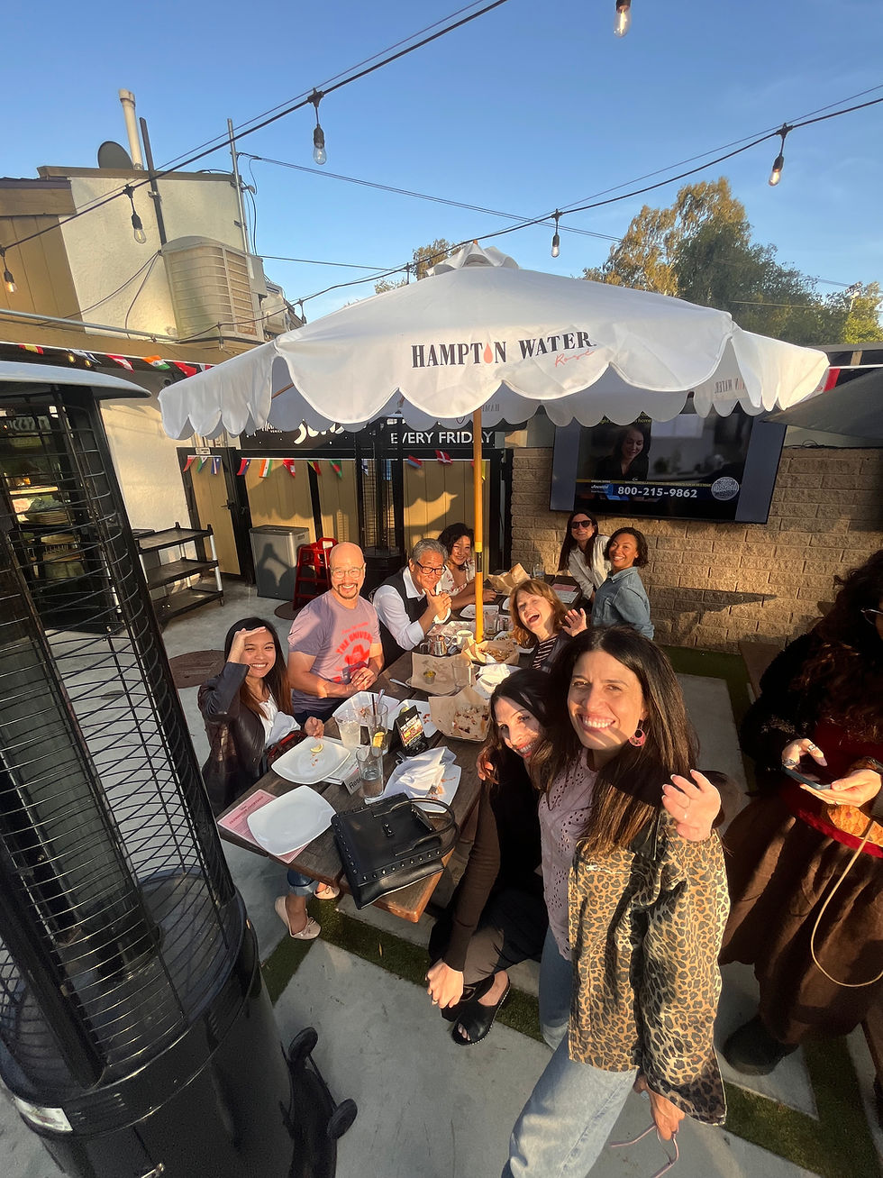 Group of People around a table with an umbrella smiling