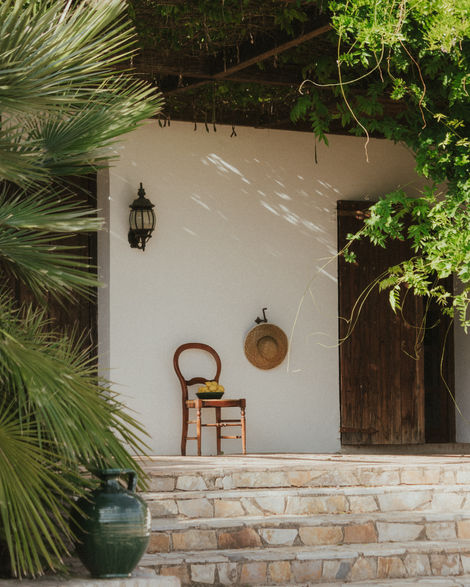 a straw hat hangs on a wall next to a chair