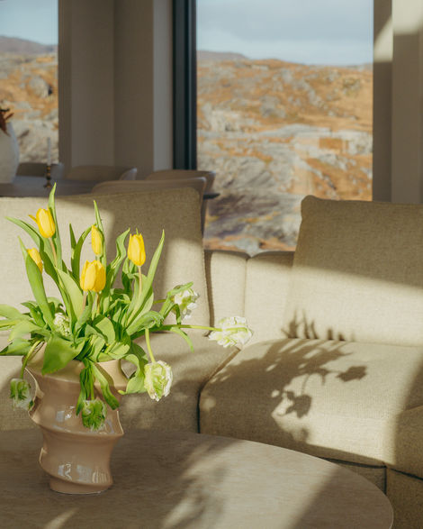 a vase of yellow tulips sits on a table in front of a window