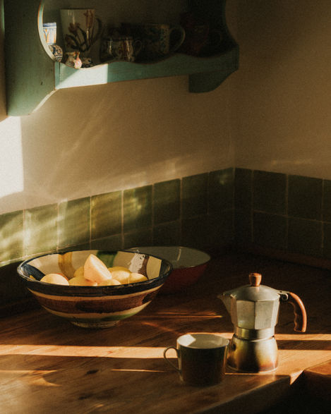 a bowl of potatoes sits on a counter next to a coffee pot