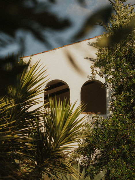 a white building with arched windows is surrounded by palm trees