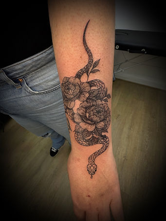 tatouage de serpent avec des fleurs pivoines sur un bras réalise par xam tattoo a marange-silvange