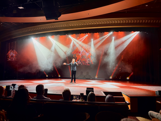 Tom Powell performing as a cruise headliner on Ambassador Ambition, showcasing professional setup and lighting