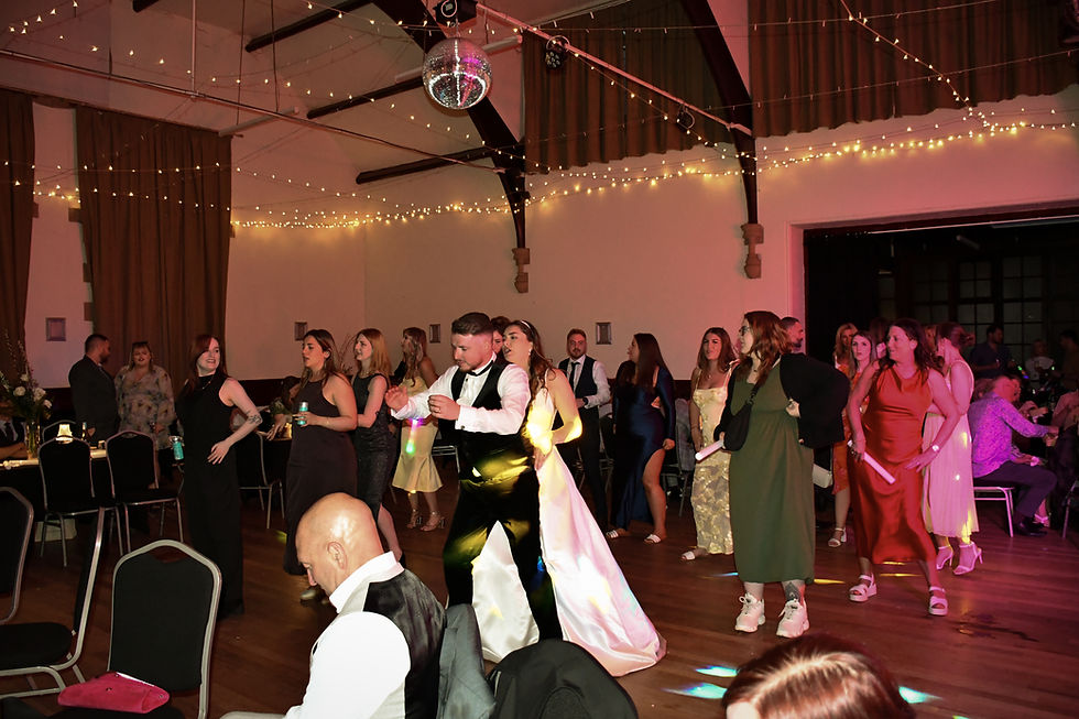 Eye-level view of a lively wedding dancefloor with guests dancing under warm lighting