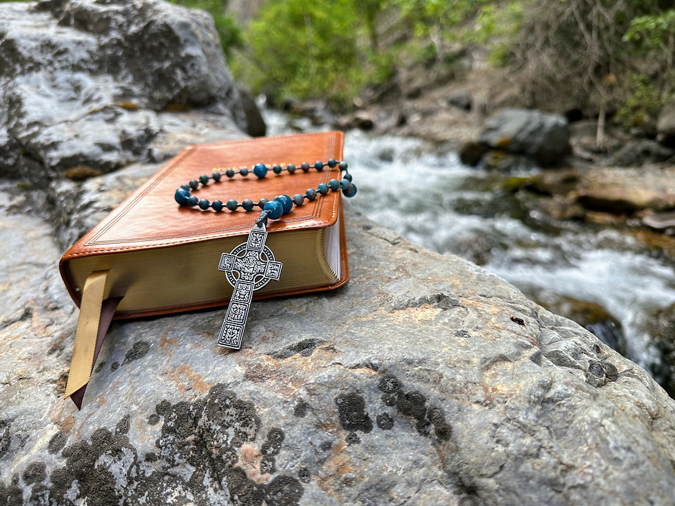Anglican Rosary with a celtic high cross alongside a Holy Bible near a river