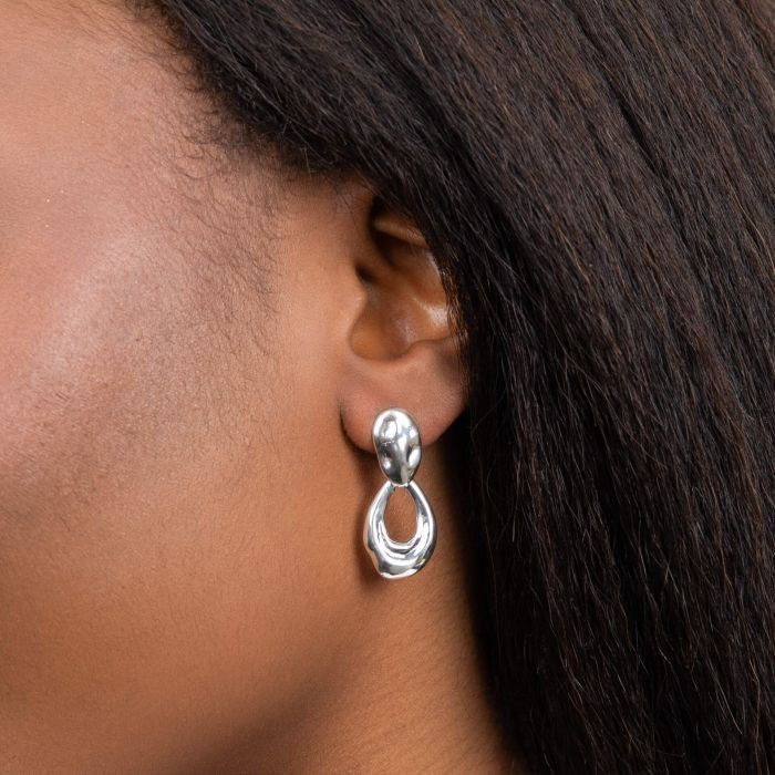 Woman wearing Molten Door knocker Earrings; silver teardrop earrings on display Léonce & Co.