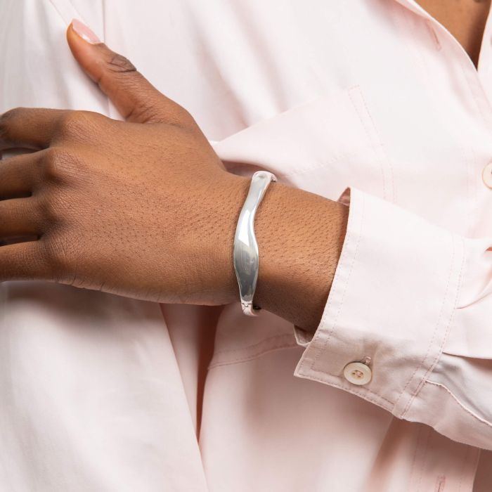 Woman wearing silver Organic Wave Statement Hinged Bangle on wrist, Léonce & Co.