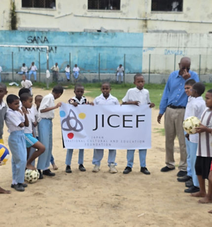 世界の孤児院・学校を支援するJICEFのプログラムで、子どもたちと共にJICEFの横断幕を掲げている現地の学校児童とスタッフの様子