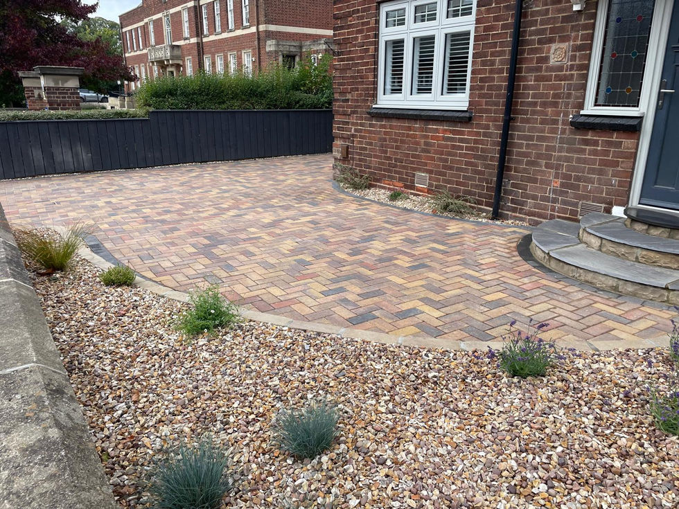 Curved block paving driveway with low-maintenance planting and brick boundary wall.