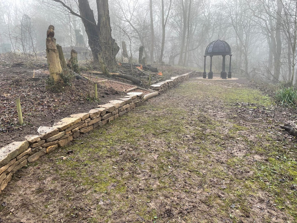 Natural stone retaining wall supporting woodland garden levels