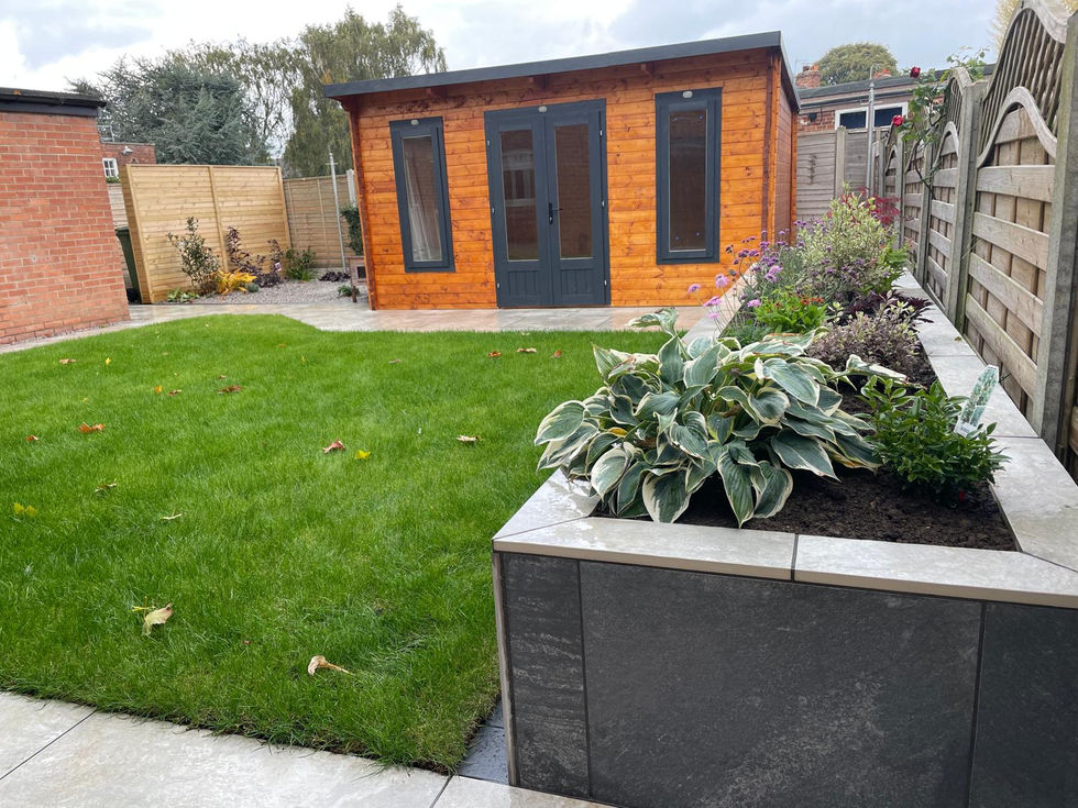 Modern raised planter with slate cladding, filled with lush hostas and seasonal plants.