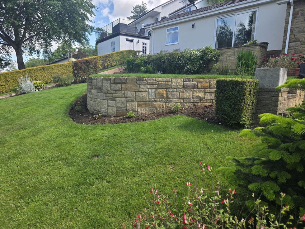 Curved natural stone retaining wall set within a mature landscaped front garden with established lawns and planting.