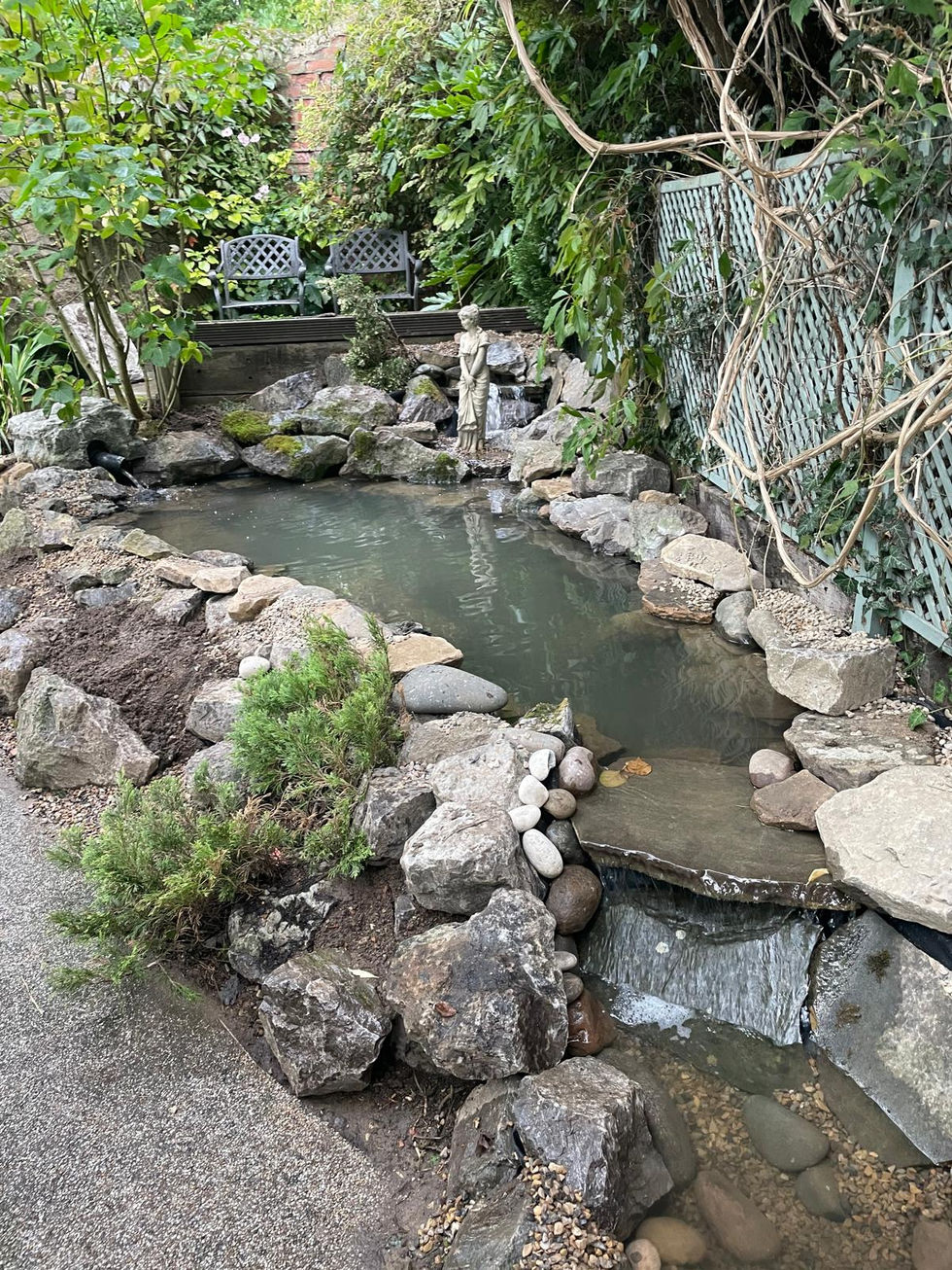 Stepped stream with small cascades and pebble beds leading down to the pond.